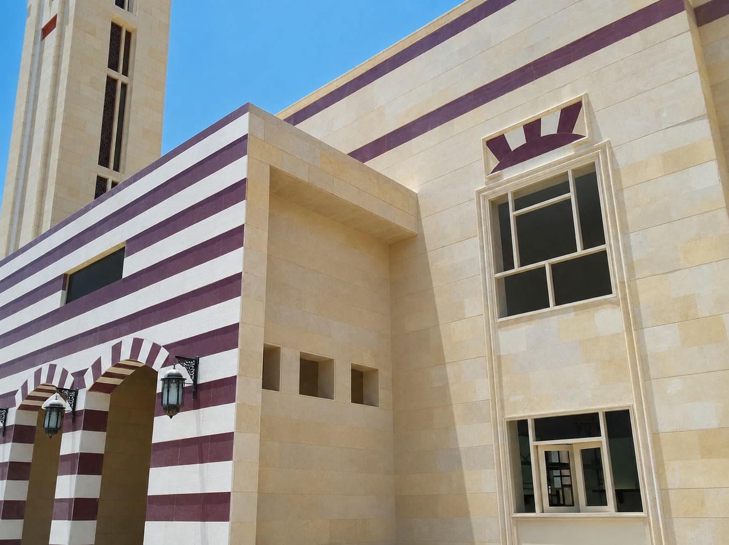 Masjed Almadina — stone facade with banded cladding and arched entrance