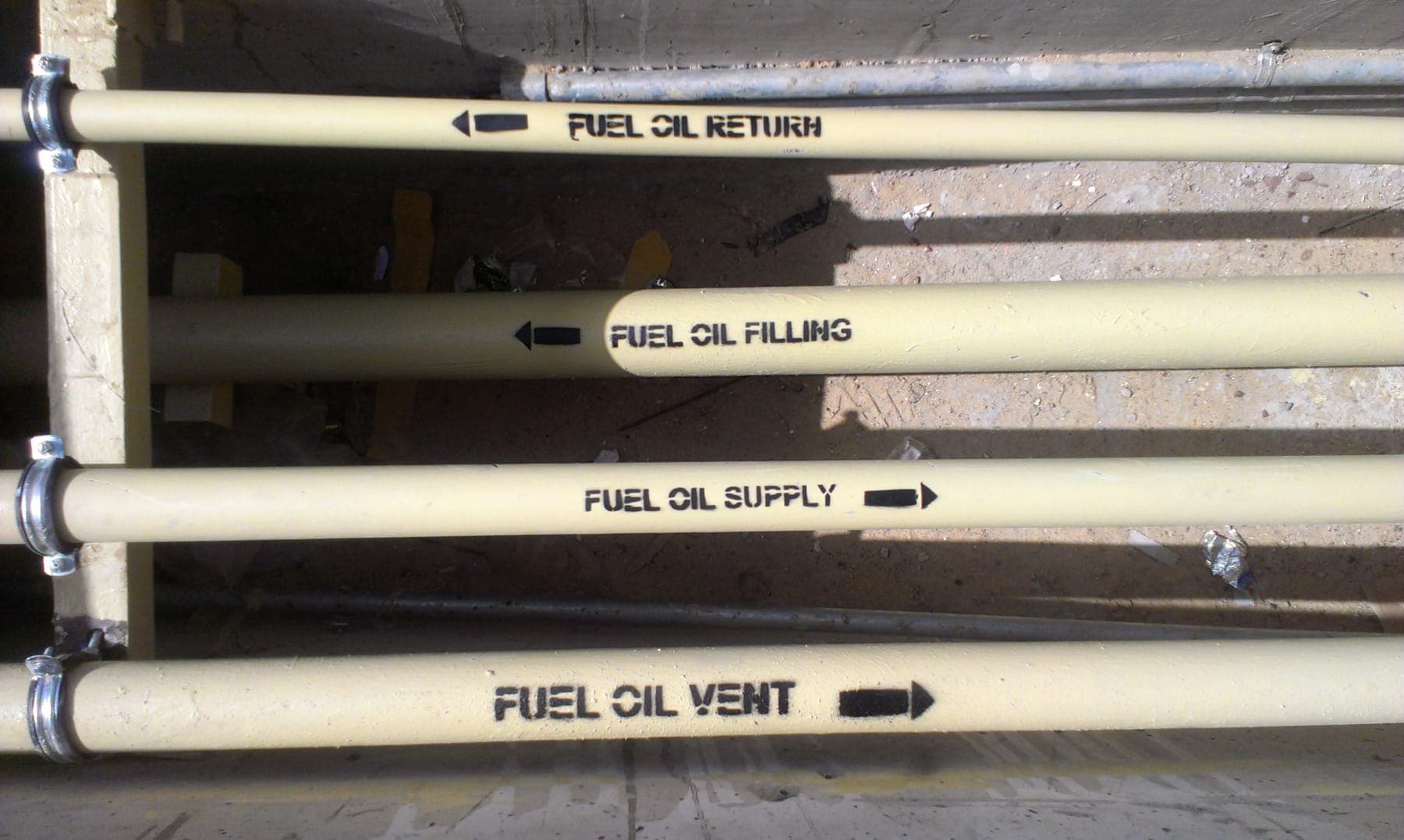 Fuel-oil pipework with stencilled flow labels and direction arrows: fuel oil return, filling, supply and vent lines