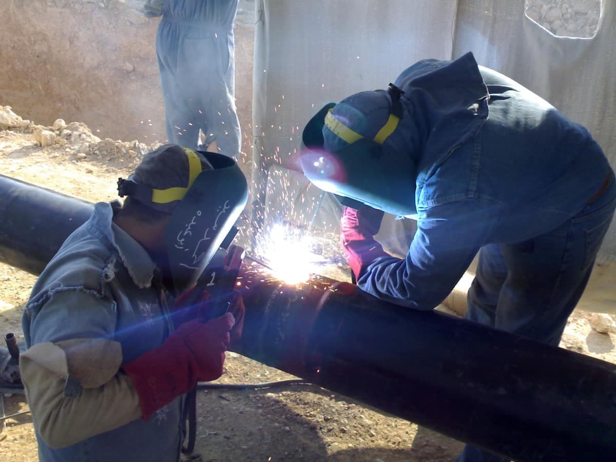Two welders joining a section of jet-fuel pipeline at the Hurghada depot